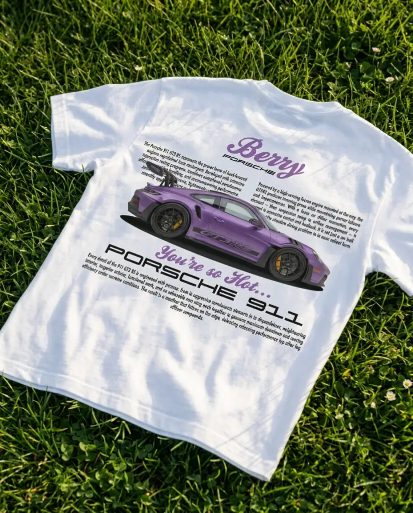 Biała koszulka z nadrukiem fioletowego Porsche 911 GT3 RS leżąca na trawie