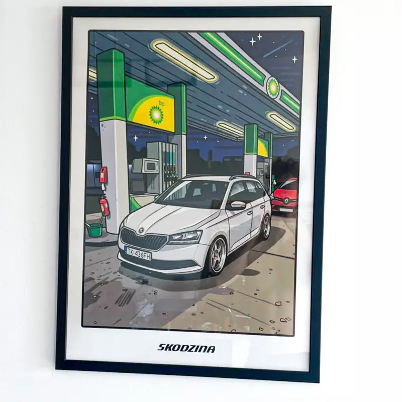 Plakat motoryzacyjny z białą Skodą Fabią na stacji paliw w ramie na ścianie